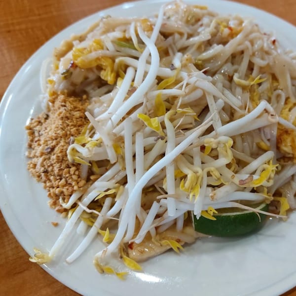 Som Jai Thai Cuisine's Pad Thai with bean sprouts, crushed peanuts, and a lime wedge.