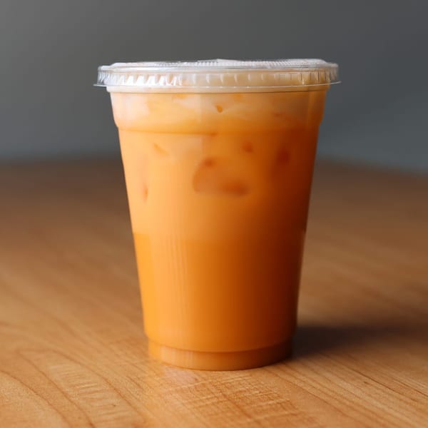 A plastic cup of Som Jai Thai Cuisine's iced Thai tea with a clear lid.